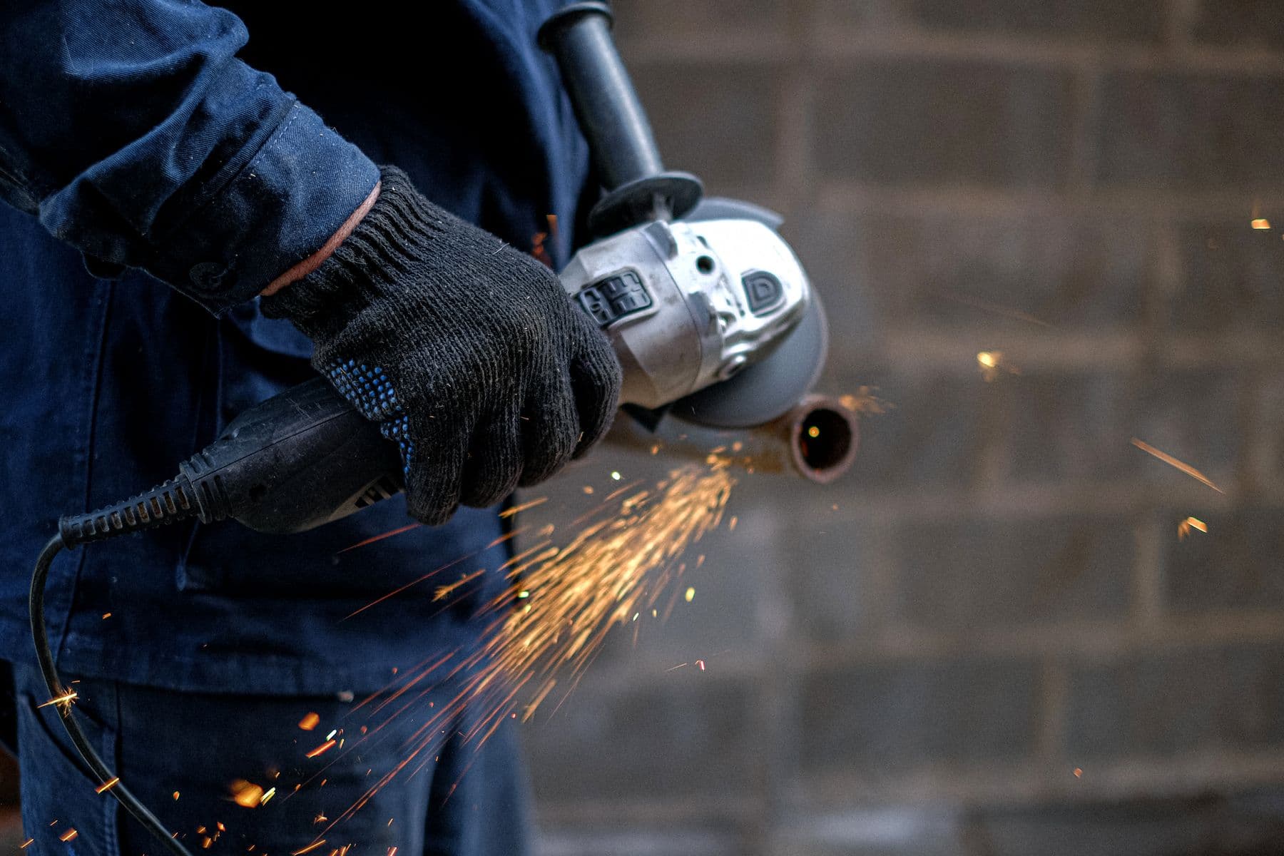 A tradesperson cutting metal, sparks flying