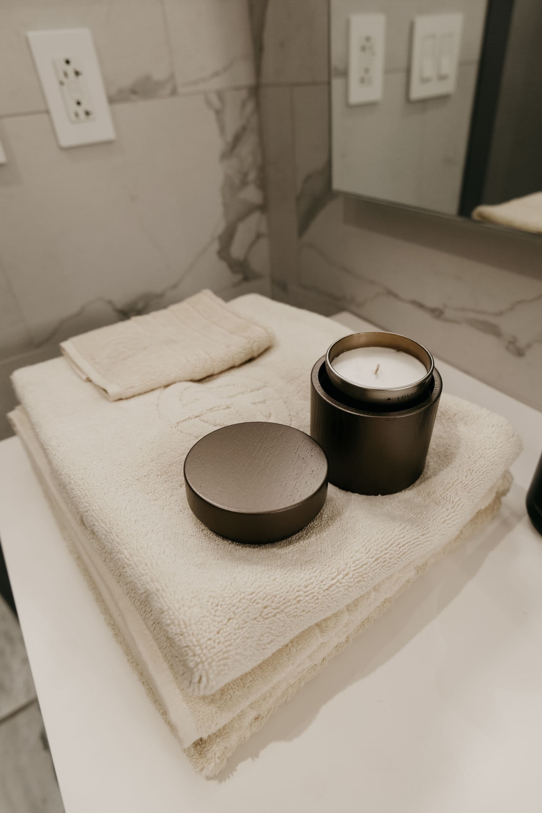 Folded spa towels and a candle on marble