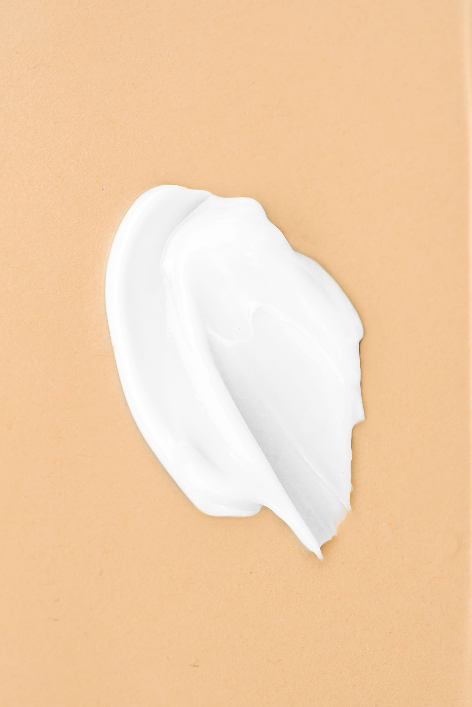 Smear of white cream on a beige surface